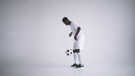 Cámara-Lenta:-Un-Jugador-De-Fútbol-Africano-Con-Camiseta-Blanca-Haciendo-Malabarismos-En-Silueta-Sobre-Fondo-Blanco.-Un-Jugador-De-Fútbol-Brasileño-Negro-Silueta-De-Hombre